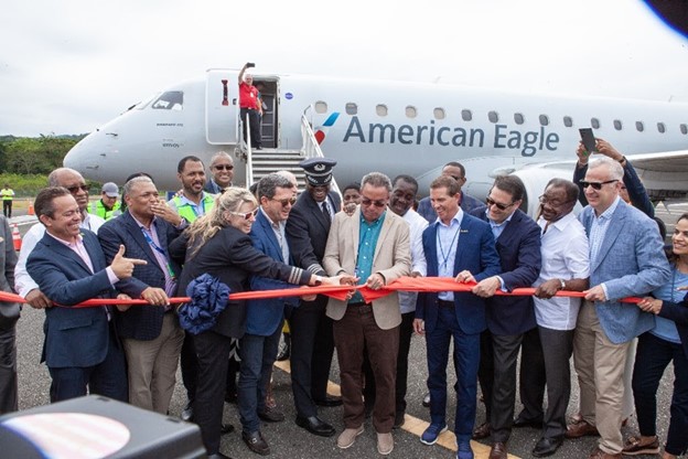 The Hon. Daryl Vaz Minister of Energy, Science and Technology, MP (center) cuts the symbolic ribbon with partners and stakeholders to commemorate the arrival of American Airlines Flight AA 4007 at Jamaica’s Ian Fleming International Airport.
