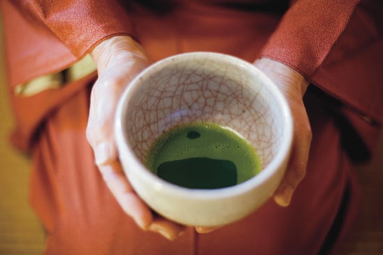 Japanese woman holding green tea in a cup
